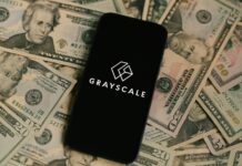 Grayscale Logo auf Smartphone, das auf Dollarscheinen liegt