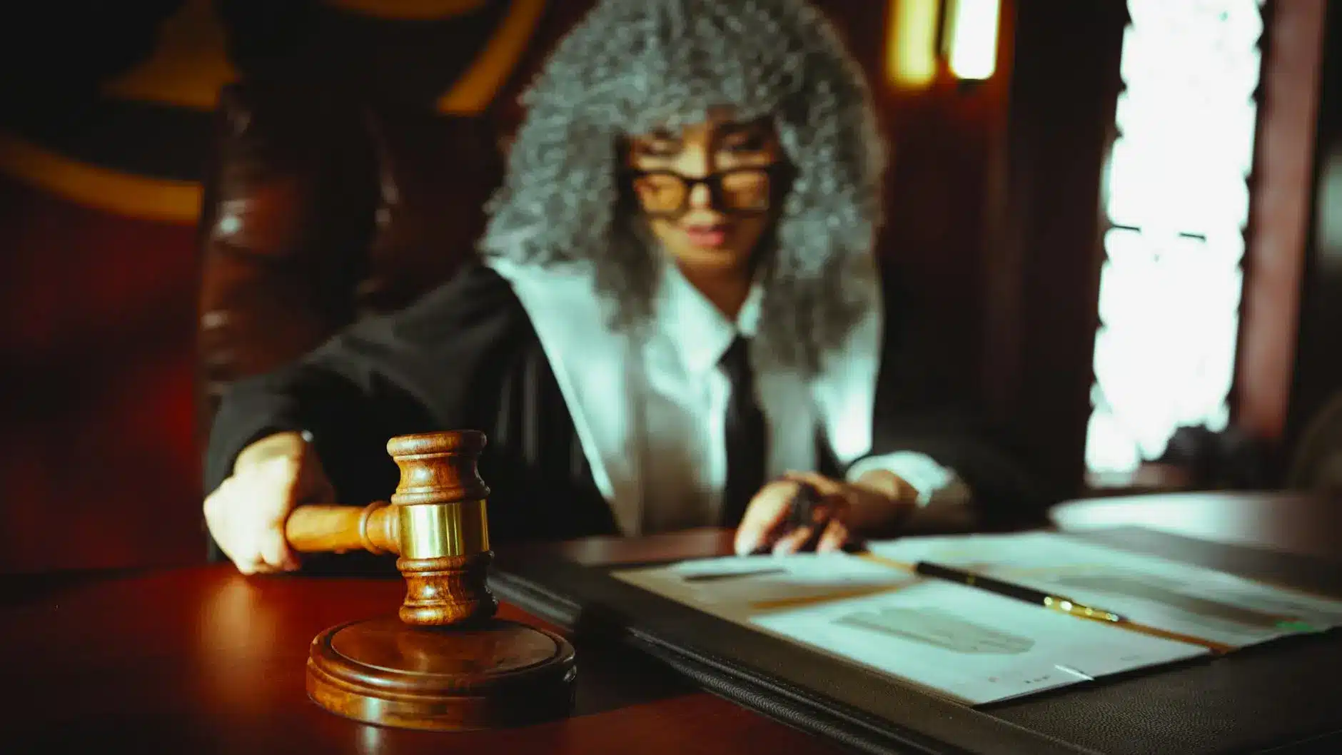 A judge in robes with a gavel on a legal desk, symbolizing courtroom decisions.
