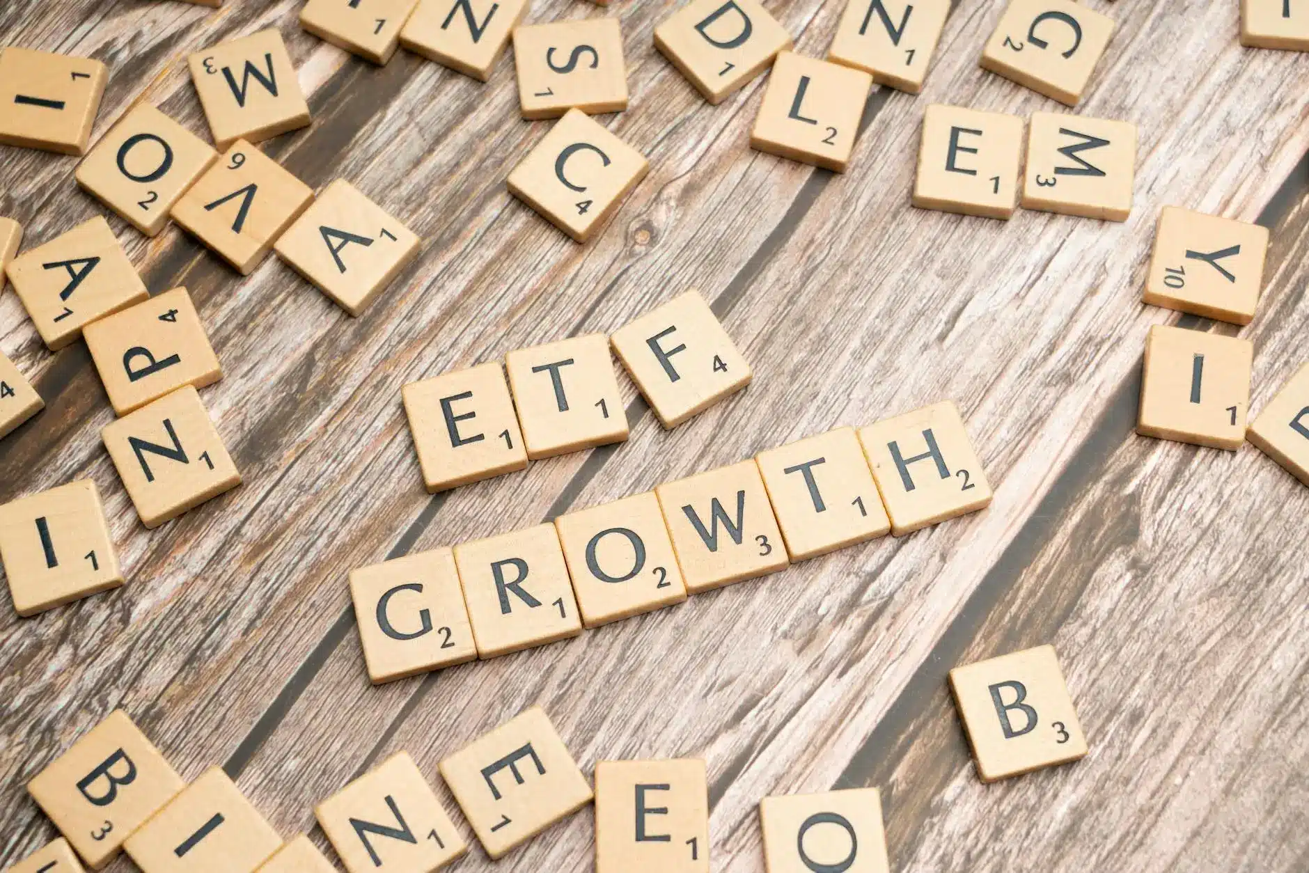 Scrabble tiles spelling 'ETF' and 'GROWTH' on a wooden background.