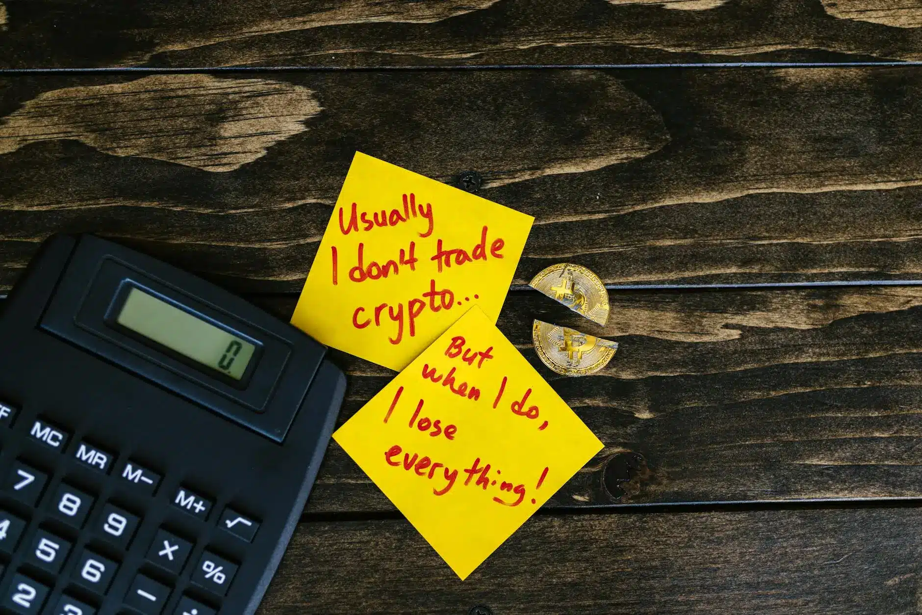 Calculator next to two sticky notes with handwritten cryptocurrency trading quotes.