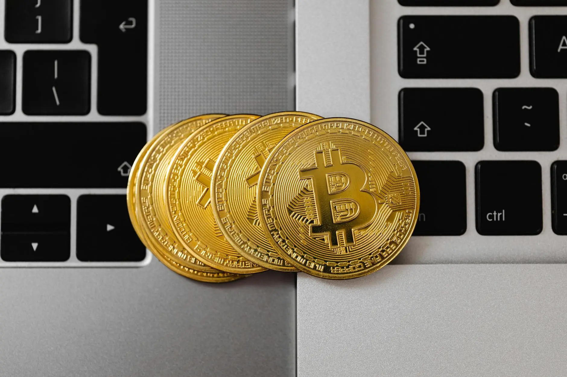 Gold Bitcoin coins on a laptop keyboard, symbolizing cryptocurrency.