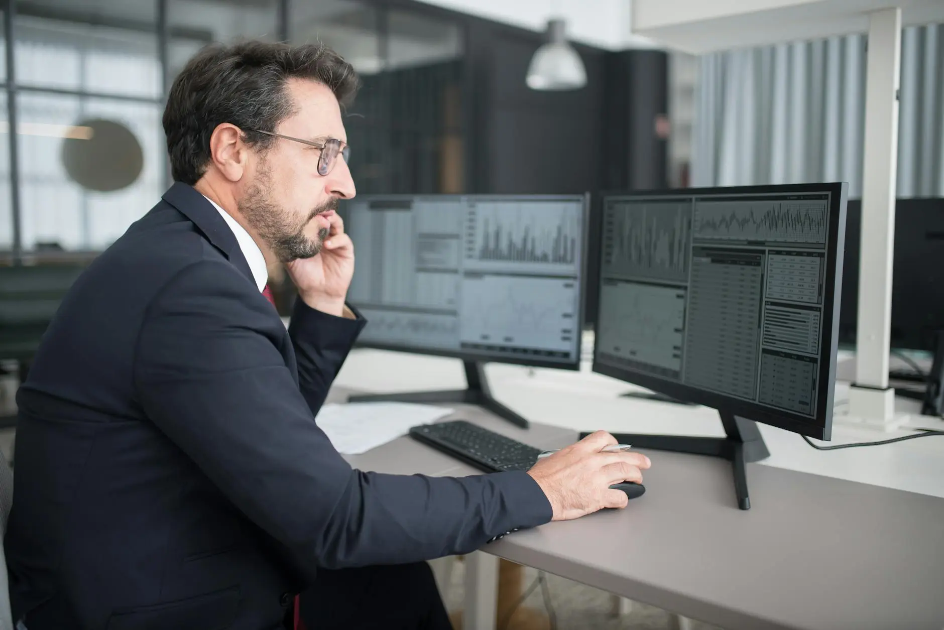 Businessman analyzing financial data on multiple computer screens.