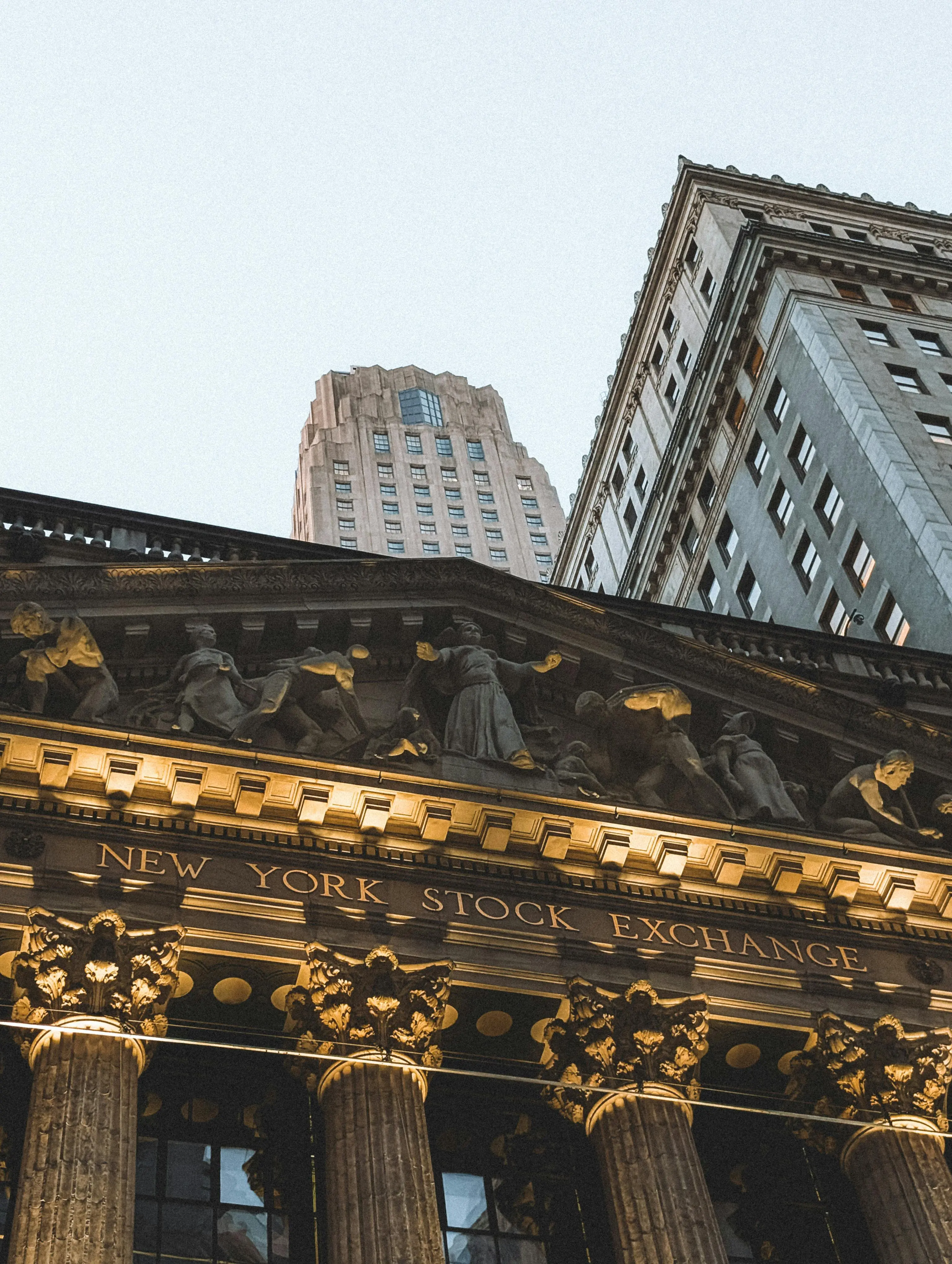 Facade of the New York Stock Exchange building with ornate columns and sculptures.