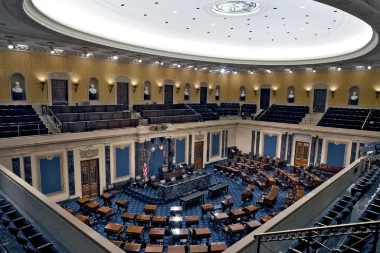 U.S. Senate chamber showing empty seats and legislative decor.