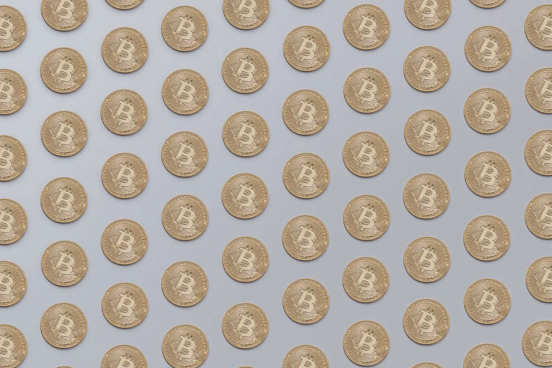 A seamless pattern of gold Bitcoin coins on a light background.