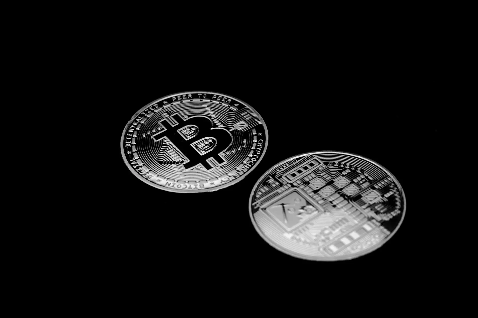 Two Bitcoin coins on a black background, showcasing detailed engravings.