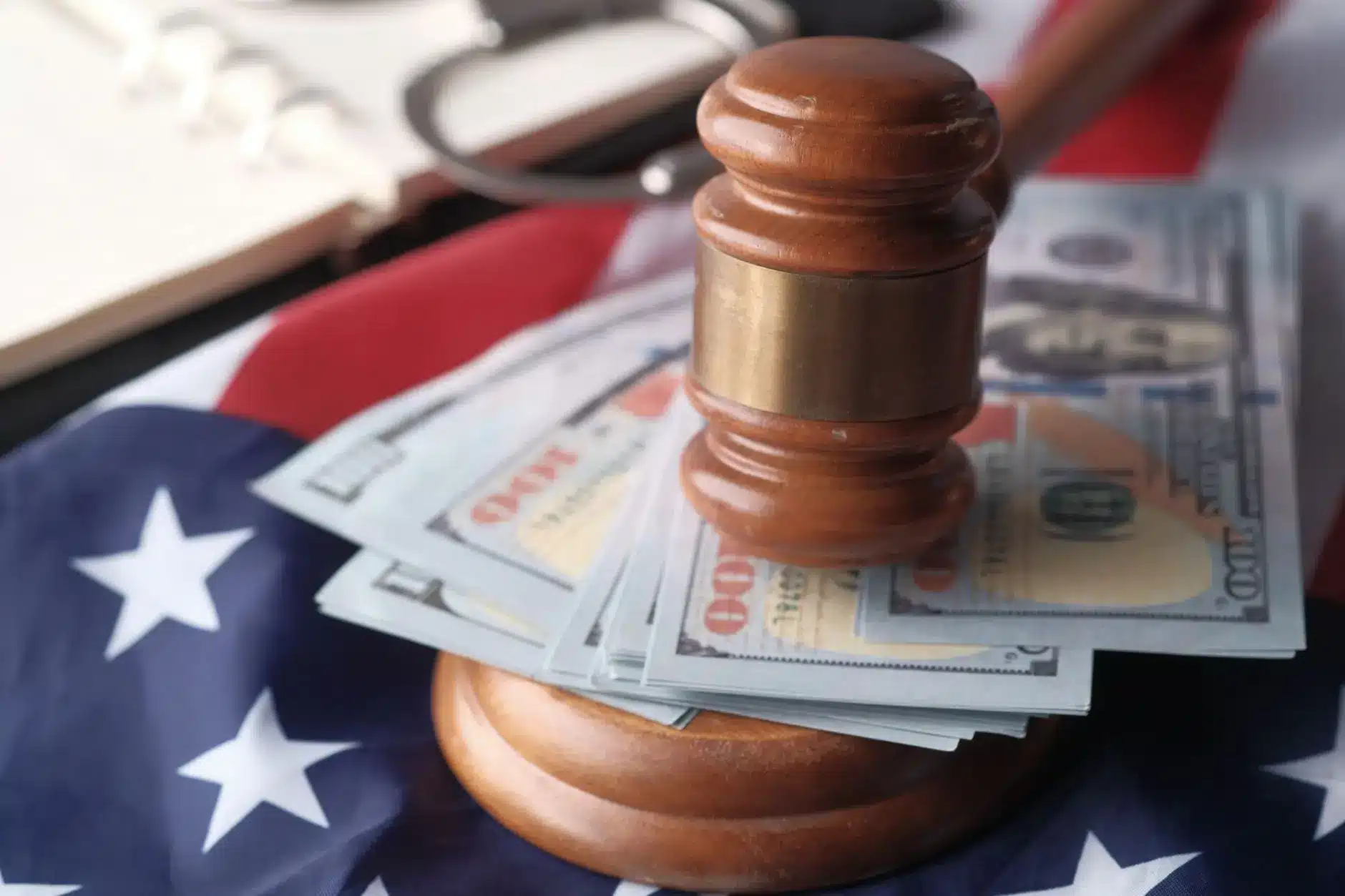 A gavel rests on a stack of hundred-dollar bills on an American flag.