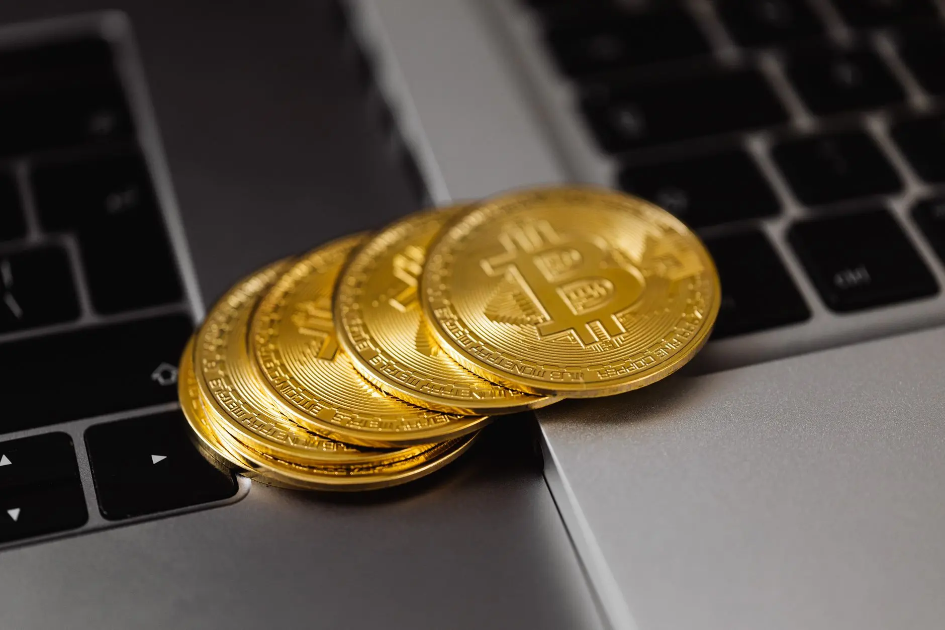 Several gold Bitcoin coins resting on a laptop keyboard.