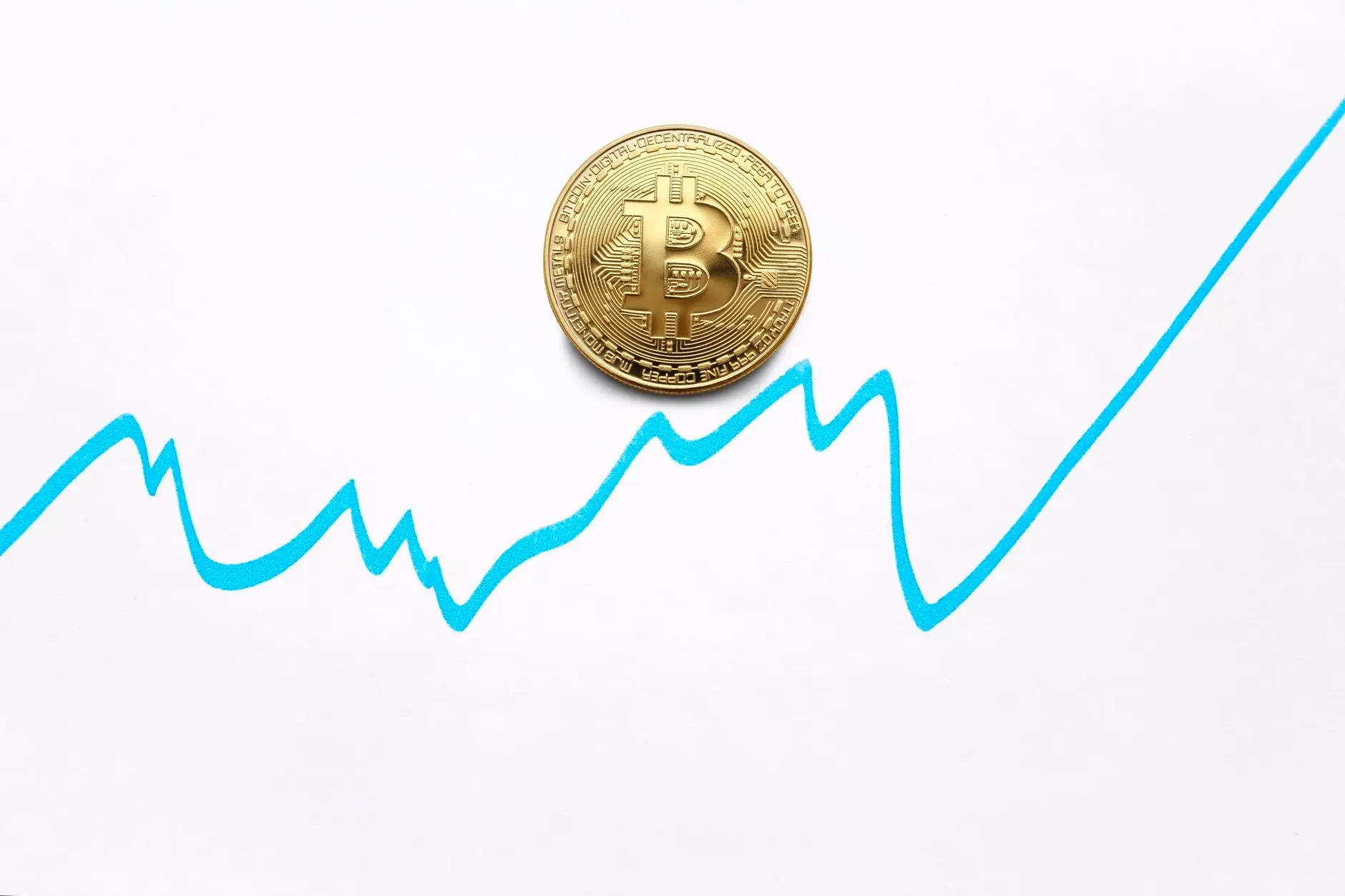 A gold bitcoin coin positioned on a graph line showing an upward trend.