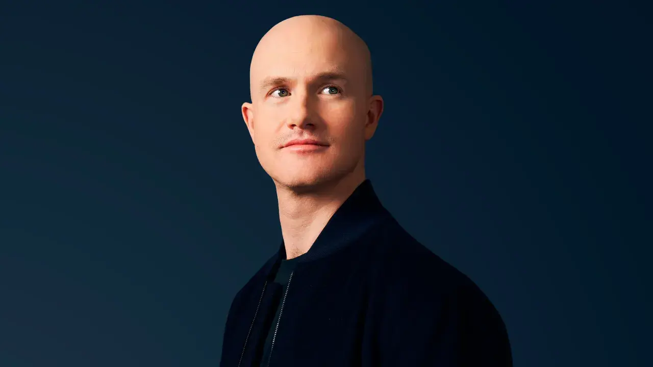 Portrait of a man with a bald head, wearing a dark jacket against a dark background.