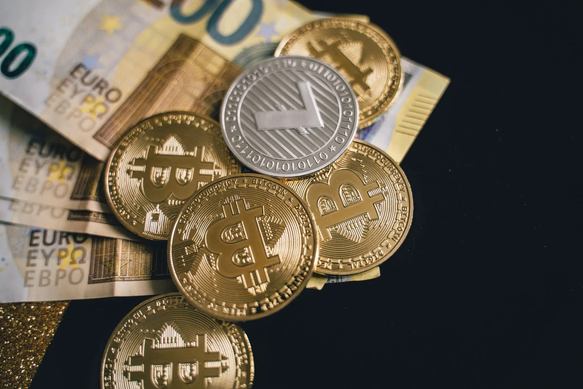 Close-up of Bitcoin and Euro banknotes on a dark surface.