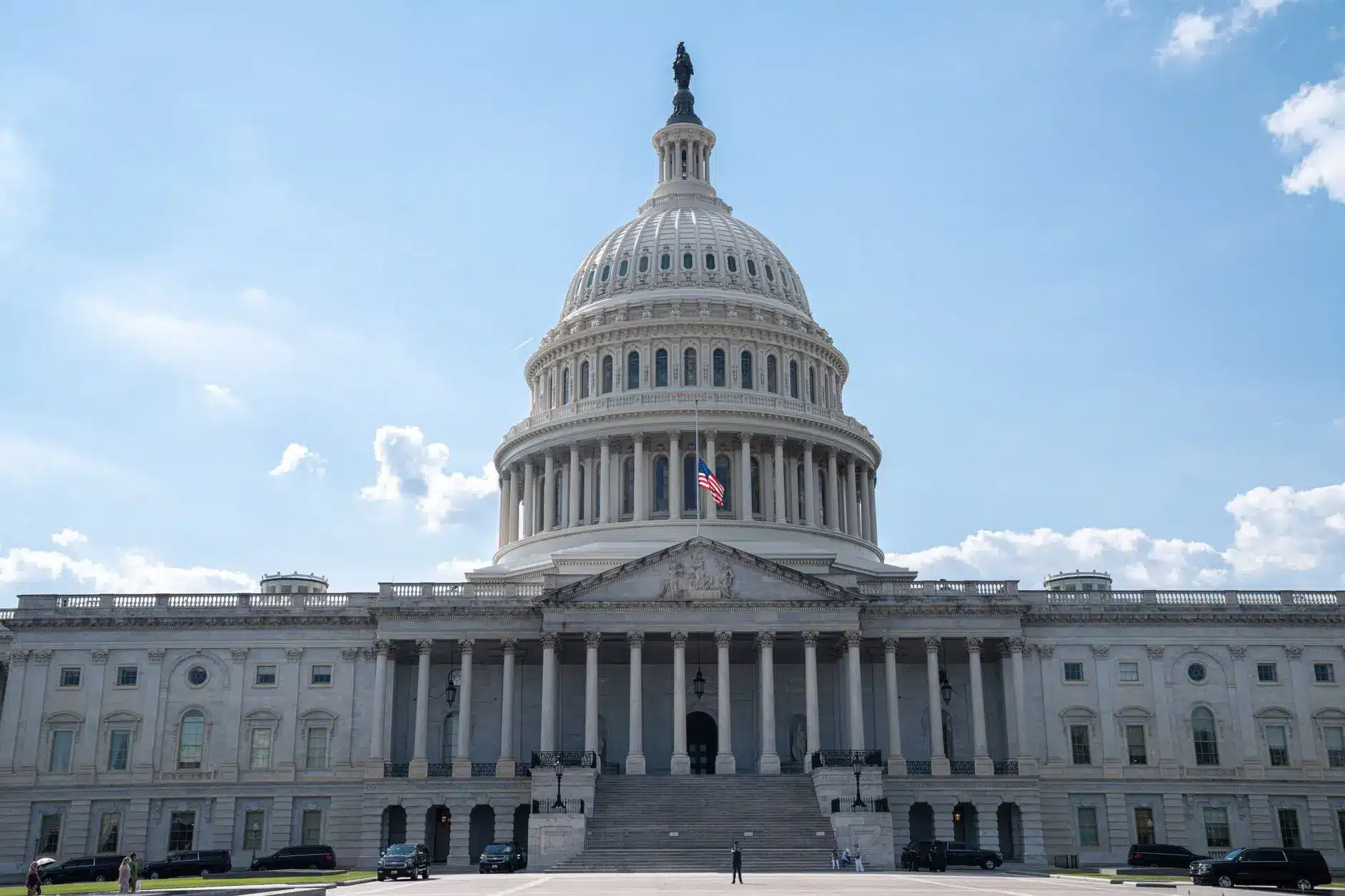 The US Capitol building in Washington, DC on a clear day with a flag flying.