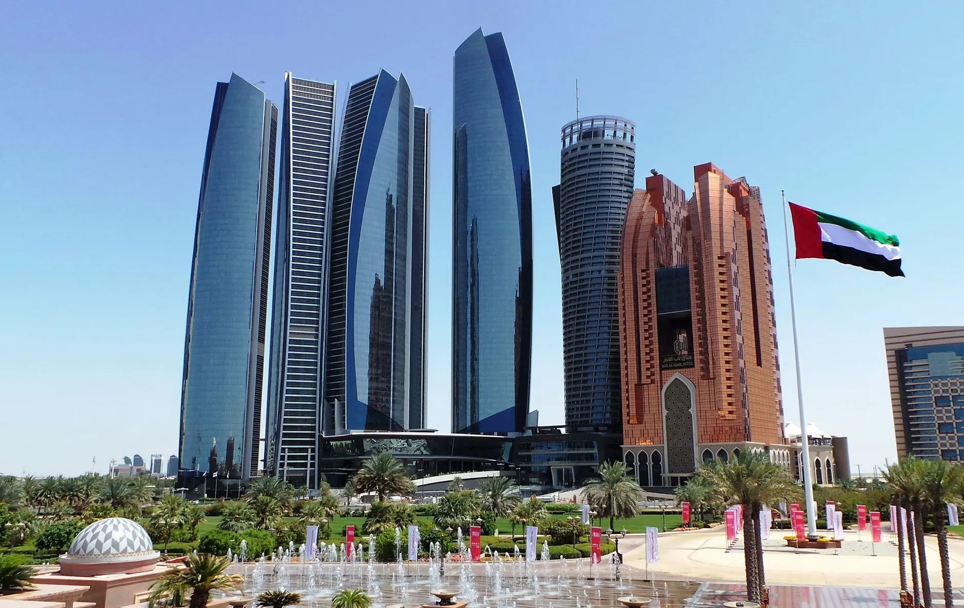 Modern skyscrapers of the Abu Dhabi Global Market financial district with the UAE flag in the foreground