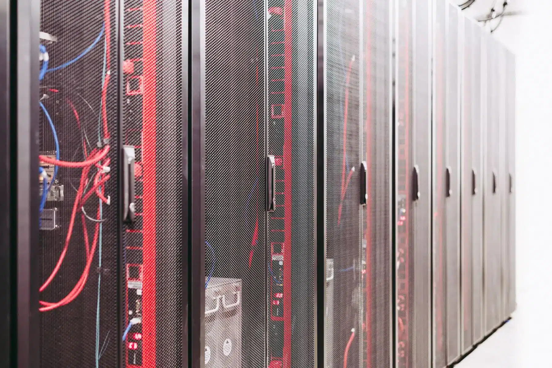 A row of server racks in a data center with red lighting and tangled networking cables