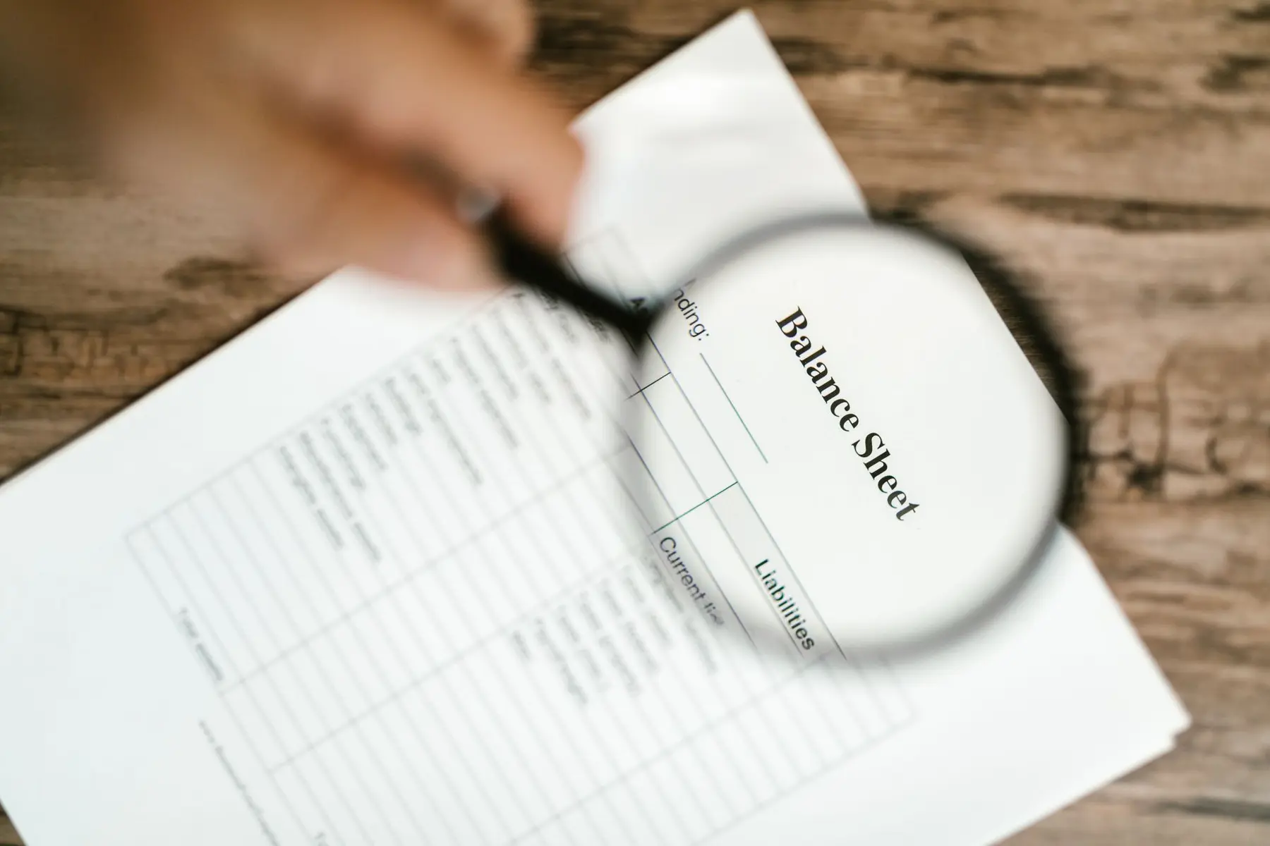 A magnifying glass focusing on the words Balance Sheet on a financial document
