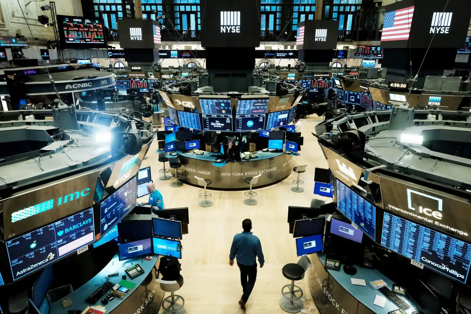 Wide shot of the New York Stock Exchange trading floor with digital monitors and traders.