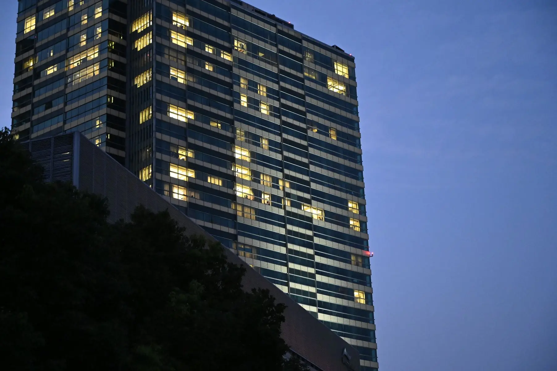 Low angle view of a modern glass skyscraper with illuminated windows at dusk