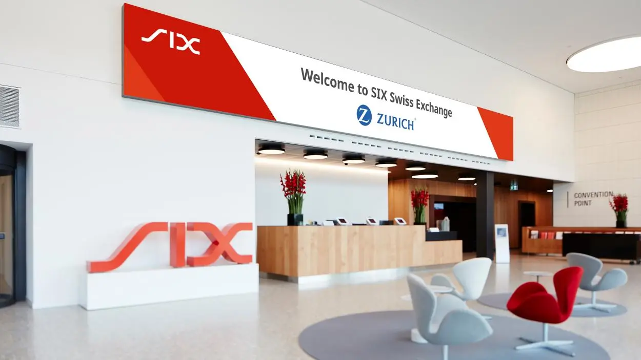 Reception area of the SIX Swiss Exchange in Zurich featuring red and white branding and modern furniture.