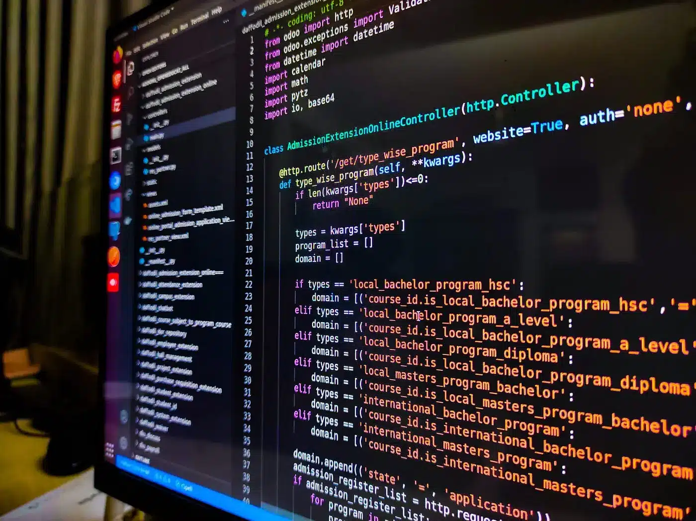 Close-up of a computer monitor displaying Python code in a dark-themed IDE with a file sidebar