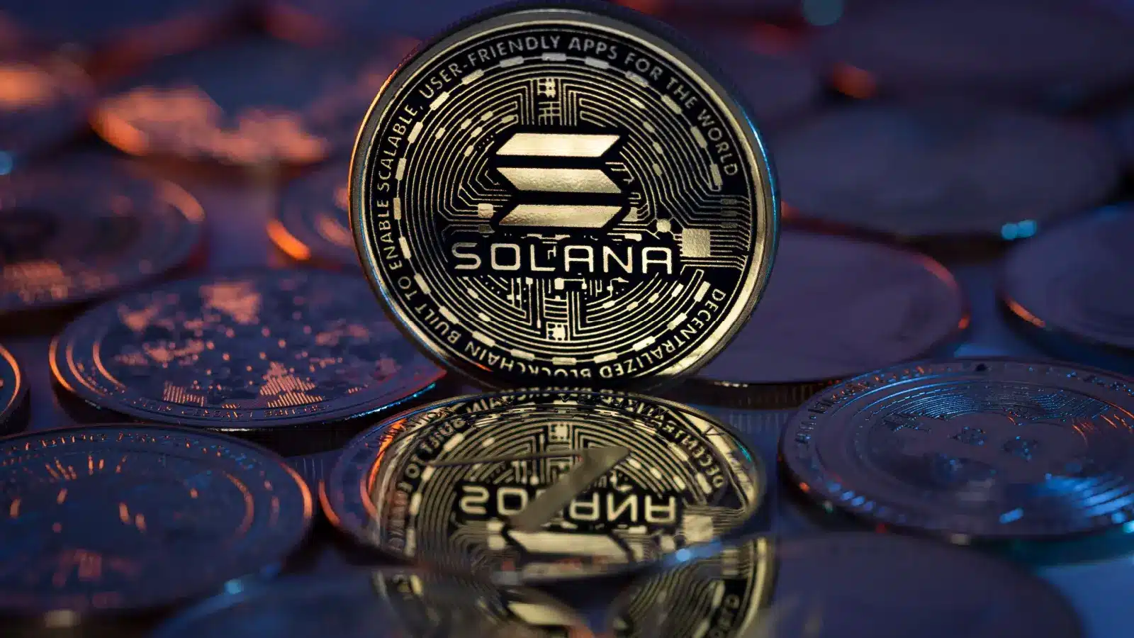 A close-up of a physical gold Solana SOL cryptocurrency coin standing upright among other blurred digital coins.