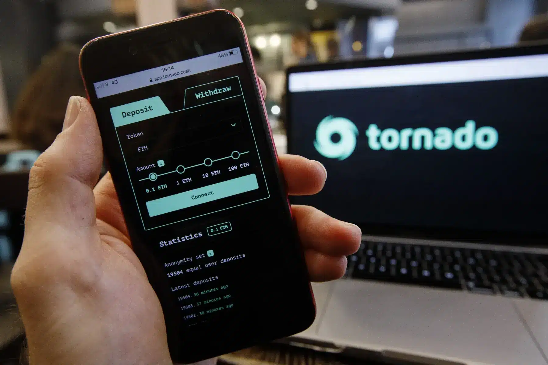 A smartphone displaying the Tornado Cash interface next to a laptop showing the Tornado logo.