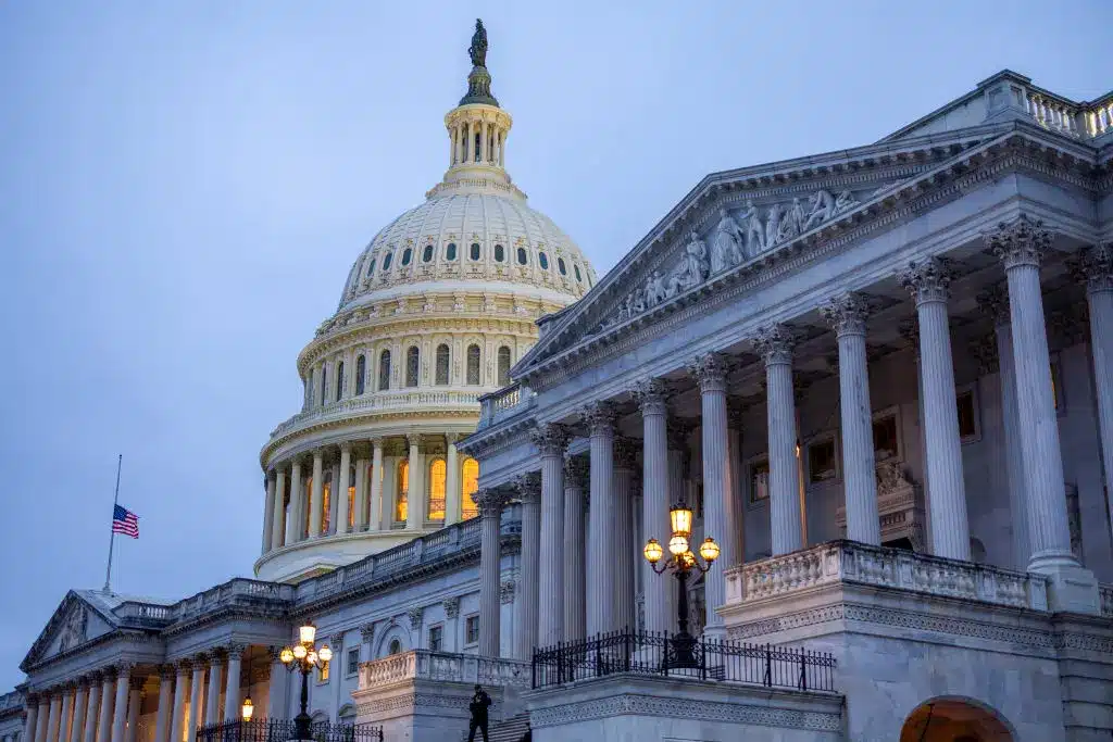 Low angle view of the US Capitol building in Washington DC at dusk with illuminated dome and columns