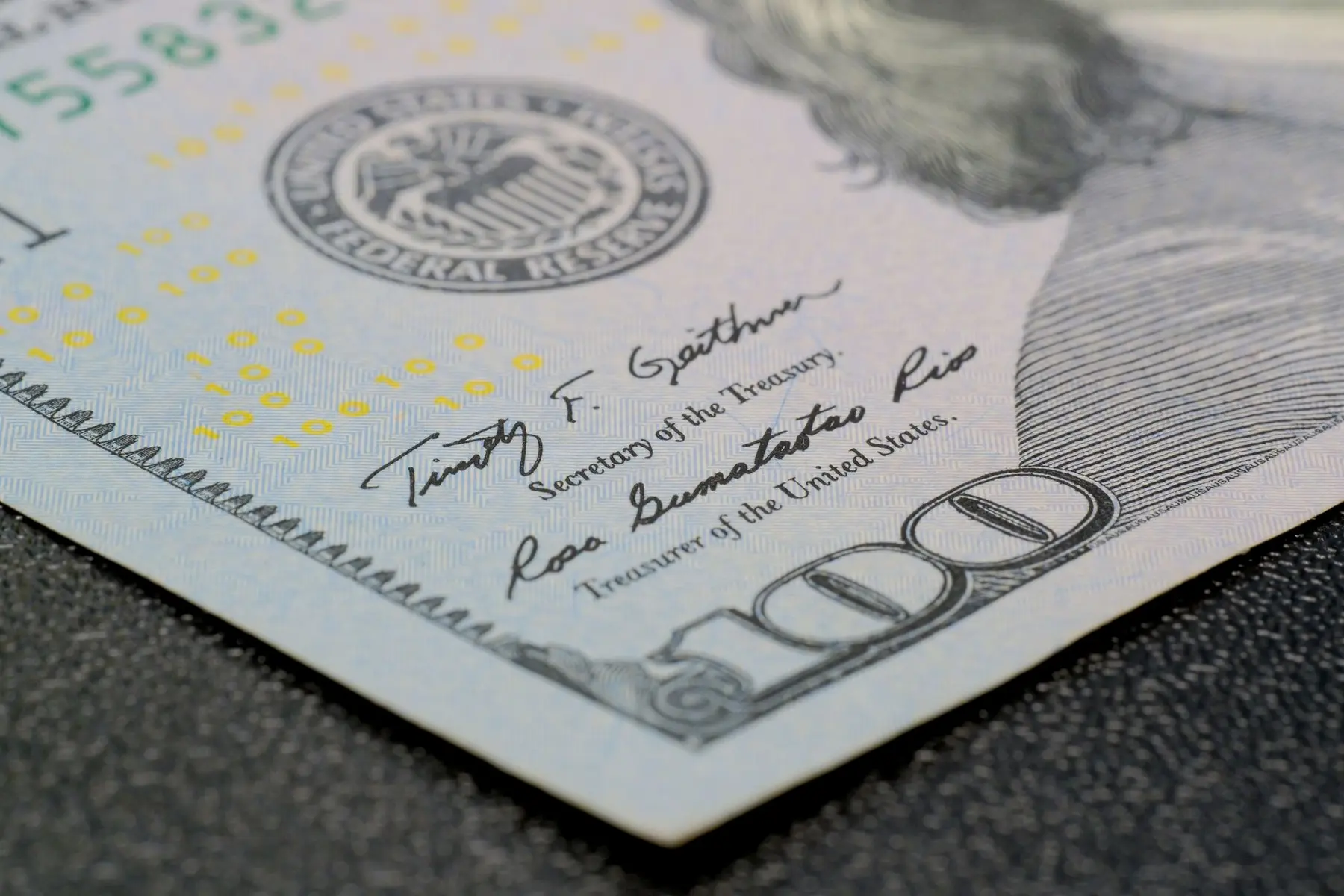 Close-up of a US 100 dollar bill showing the signatures of the Secretary of the Treasury and Treasurer.